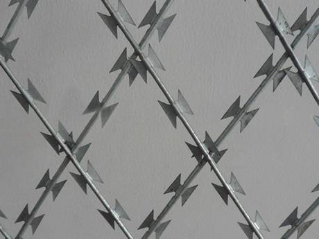 قطعة من شبكة أسلاك شائكة ملحومة من الفولاذ المقاوم للصدأ مع فتحة ماسية على خلفية رمادية.