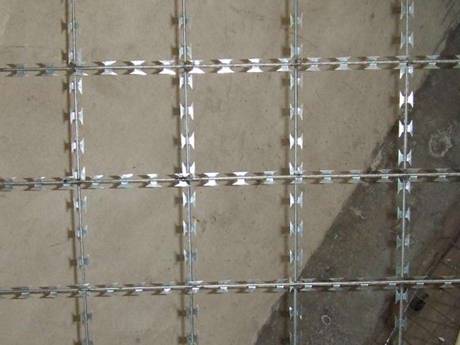 Unha peza de malla de arame soldada de aceiro inoxidable con abertura cadrada sobre o fondo gris.